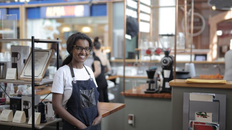 Shop worker in an apron standing beside stocked shelves