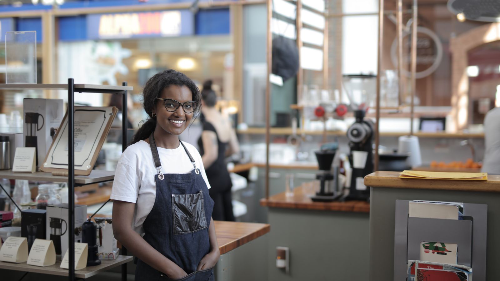 Shop worker in an apron standing beside stocked shelves