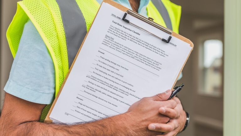Home inspector in a hi-vis vest holding an inspection checklist