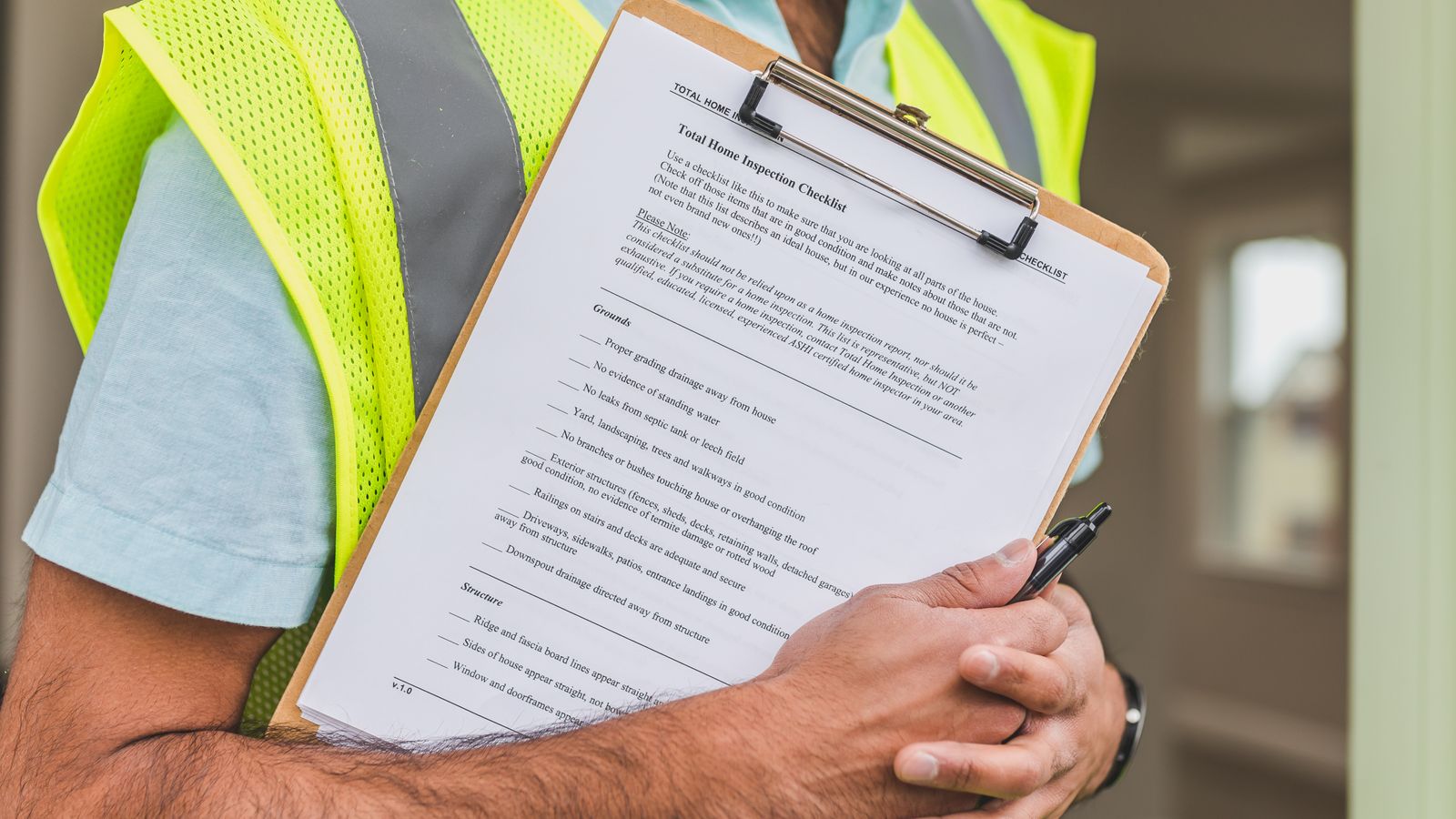 Home inspector in a hi-vis vest holding an inspection checklist