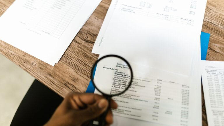 Magnifying glass held over a printed financial statement