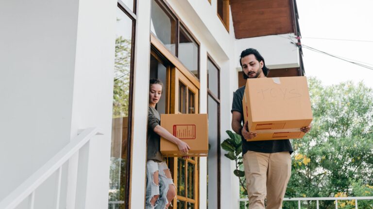 Couple carrying cardboard boxes while moving house