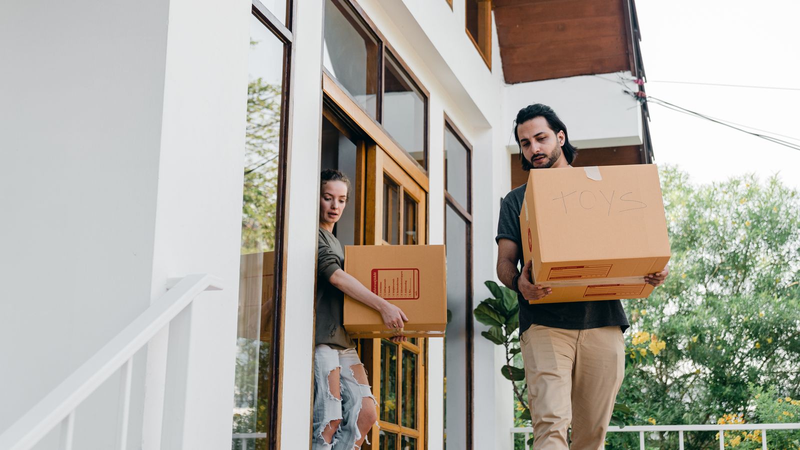 Couple carrying cardboard boxes while moving house