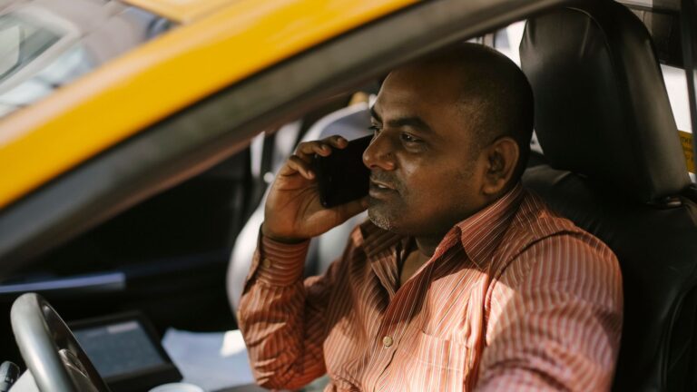 Taxi driver taking a call at the wheel